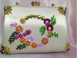 Close-up of multicolor floral sequin embroidery and beadwork on beige and golden women’s clutch